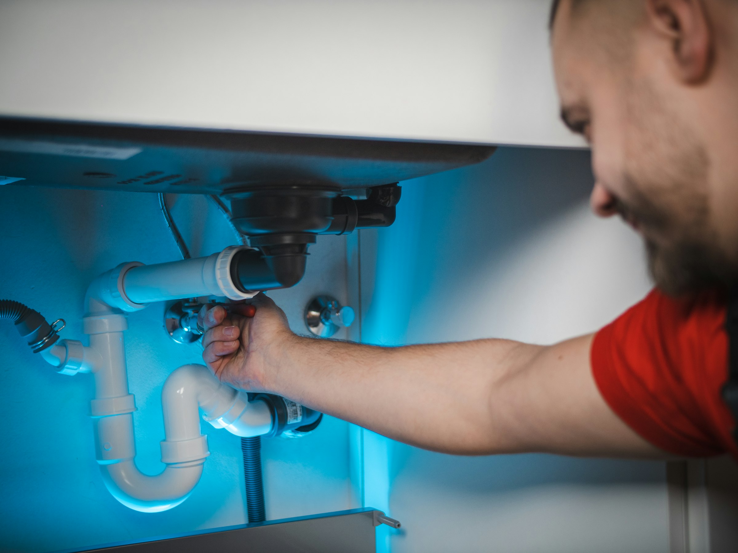 Plumber working on pipes under a basin