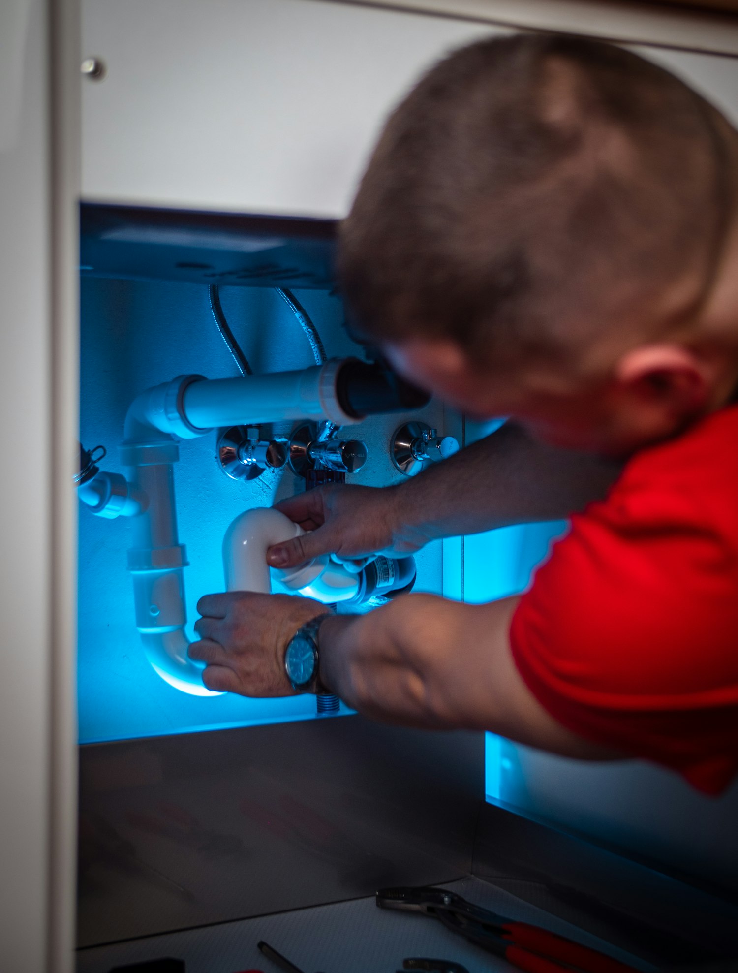 Plumber repairing a pipe under a sink